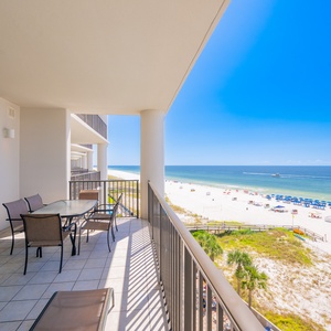 Relax on the spacious balcony with a dining table, enjoying  views of the pristine beach and vibrant blue waters