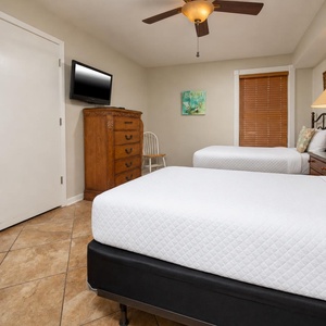 This cozy room features two comfortable twin beds, a mounted TV, and charming decor, perfect for a relaxing getaway