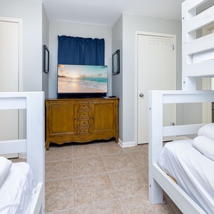 Dual twin over full bunk beds create a fun sleeping space, complemented by a wooden dresser and a TV in this cozy guest room