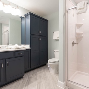 Enjoy a relaxing shower after a day at the beach in this guest bath with stylish accents and fluffy towels