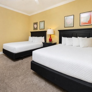 Comforting guest bedroom featuring two queen beds, stylish decor, and warm yellow walls for a cozy retreat