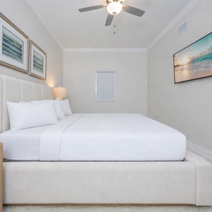 Rest in this serene guest bedroom featuring a plush bed, soft linens, and a TV