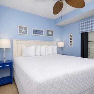 This inviting bedroom features a comfortable bed, cheerful blue walls, and charming coastal decor for a relaxing stay