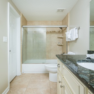 Refresh in this stylish guest bathroom featuring a granite vanity, glass tub-shower, and soft towels for your comfort