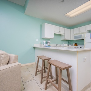 Prepare meals in this functional kitchen with a breakfast bar, essential appliances, and a refreshing color scheme