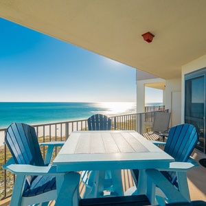 Balcony with a light blue table and chairs offers a breathtaking view of the gulf and the beach below