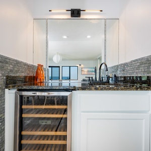 Stylish wet bar featuring sleek black fixtures, granite countertops, and a wine fridge, perfect for entertaining guests