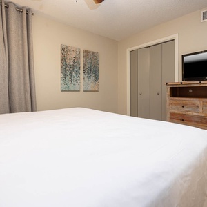 The cozy guest bedroom features a king bed, stylish artwork, and a rustic dresser with a TV for entertainment