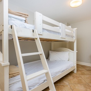 This cozy room features a charming white twin bunk bed, perfect for kids, with soft linens and a stylish dresser nearby