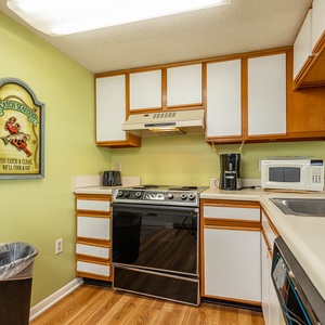 This kitchen features wood cabinetry, a black stove, dishwasher, and a charming seafood sign for a fun cooking experience