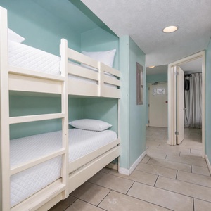Cozy bunk beds provide a fun sleeping option for kids, with fresh linens and a cheerful aqua wall color