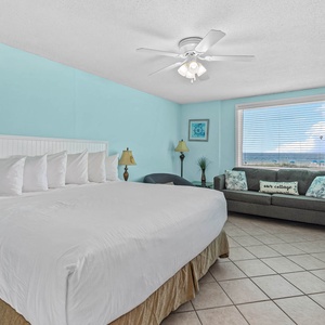 Master bedroom featuring a king-size bed, cozy chair and sofa with queen sleeper, balcony access and a lovely beach view