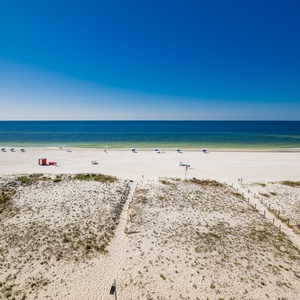 This stunning beachfront view showcases soft white sand and inviting blue waters, perfect for a relaxing getaway