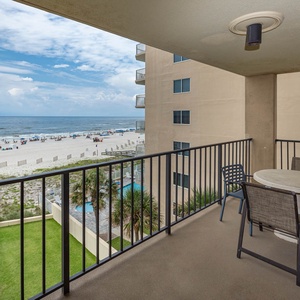 Enjoy the inviting balcony with a table and chairs, offering a beautiful view of the beach and vibrant shoreline activities