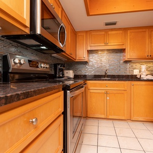 The kitchen features stainless appliances, granite countertops, and a stylish backsplash, perfect for culinary adventures