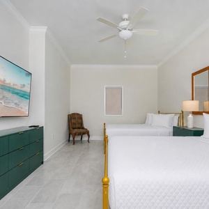 Relax in this spacious guest room featuring two queen beds, a large TV, and a stylish dresser