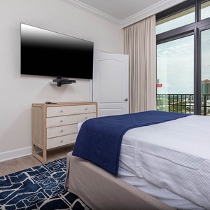 This bedroom features a cozy design with a TV mounted on the wall and a stunning beachfront view through large windows