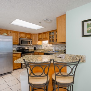 Granite breakfast bar invites you to chat and sip morning coffee in this kitchen