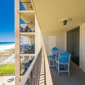 Your balcony offers a bright getaway with blue chairs and a sweeping view of the beach and coast beyond