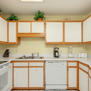 The kitchen features light cabinetry, a double sink, and essential appliances, creating a functional cooking space
