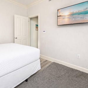 Peace settles in the guest suite as you rest looking up at the TV with coastal scenes and gentle hues on the walls