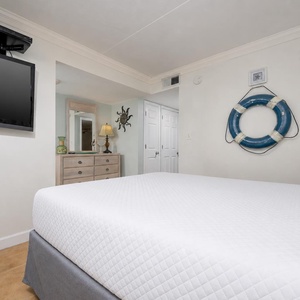 This inviting room features a comfortable bed, a mounted TV, and coastal decor, perfect for a relaxing getaway