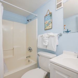 Refresh yourself in the guest bath featuring soft towels and cheerful decor, perfect for your beach retreat