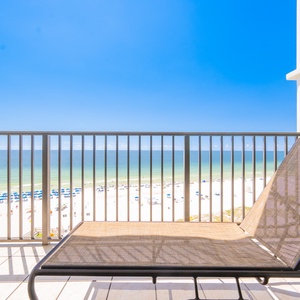Relax on the balcony lounge chair with breathtaking views of the beach and tranquil blue waters