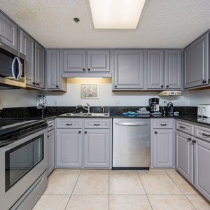 Modern kitchen features sleek gray cabinetry, granite countertops, and stainless appliances, perfect for preparing meals