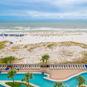 Relax by the lazy river with a captivating view of the serene beach and vibrant blue umbrellas in the distance