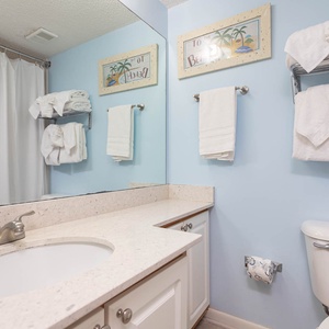 Guest bathroom featuring a spacious vanity with a circular sink, ample towels, and a relaxing beach-themed decor