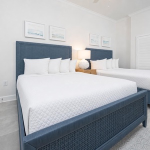 Settle into the queen beds with woven blue headboards in this guest suite and read by the warm bedside lamp
