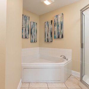 The master bathroom features a relaxing jetted tub, separate modern shower, and artistic wall decor for a refreshing retreat