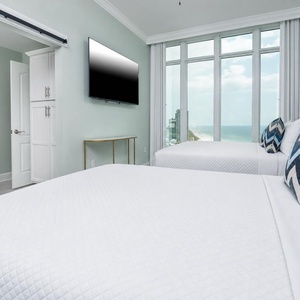 Curl up on a comfy queen bed, gaze at the beach through towering windows, and enjoy a good movie