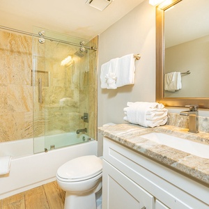 Indulge in a refreshing shower, surrounded by elegant tiles and fluffy towels in the guest bath