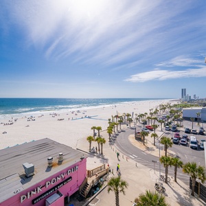 Sunlight sparkles on the coastline as you watch lively beachgoers from your balcony