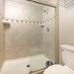 Enjoy a refreshing shower in the tiled master bathroom featuring a glass enclosure and stylish accents