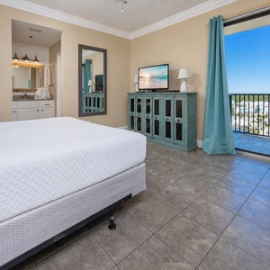 Brightly decorated master suite features a king bed, a teal accent cabinet, and a seating area with a view of the outdoors