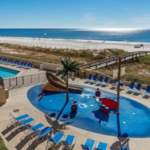 The vibrant pool area features a playful pirate ship splash park, with lounge chairs inviting relaxation by the beach