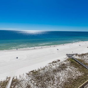 Expansive view of the tranquil beachfront with white sand and gentle waves, inviting relaxation and outdoor enjoyment