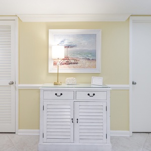 Brightly painted walls complement a white cabinet with two drawers and a lamp, enhancing the welcoming entryway atmosphere