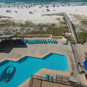 Enjoy the inviting pool area with lounge chairs, a children's play area, and a beautiful view of the beach just steps away