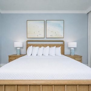 Tranquil master bedroom featuring a king bed with fluffy pillows, stylish lamps, and coastal artwork
