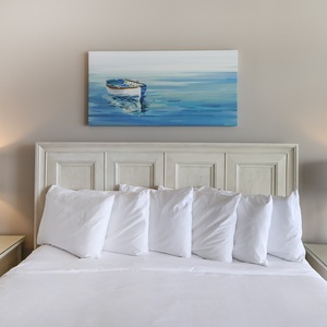 Drift into a restful sleep in the king master suite surrounded by plush pillows, with coastal art inspiring sweet dreams