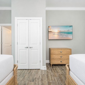Cozy guest bedroom featuring two queens, a stylish dresser, and a large TV