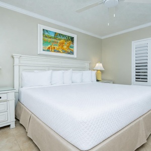Relax in this serene guest bedroom featuring a king bed, soft linens, and cheerful coastal artwork for a restful retreat