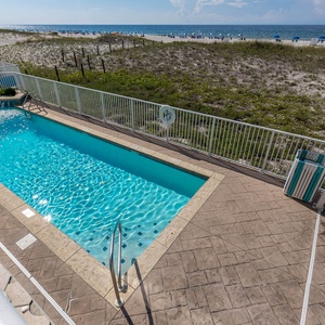 Relax by the sparkling pool with a beautiful view of the pristine beach and colorful umbrellas in the distance