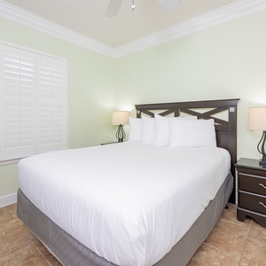 Relax in this inviting guest bedroom featuring a plush queen bed, soft linens, and calming green walls for a restful retreat
