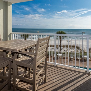 Enjoy stunning beachfront views from this balcony with a stylish wooden dining set, perfect for relaxing meals outdoors