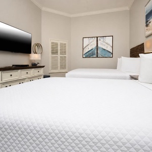 This guest bedroom features two comfortable beds, a wall-mounted TV, and coastal decor, creating a relaxing retreat